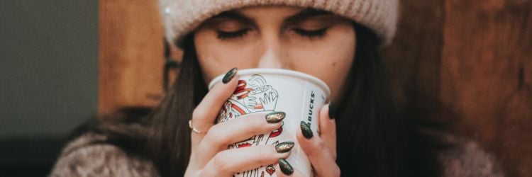 Mujer con gorro tomando un café de Starbucks de invierno