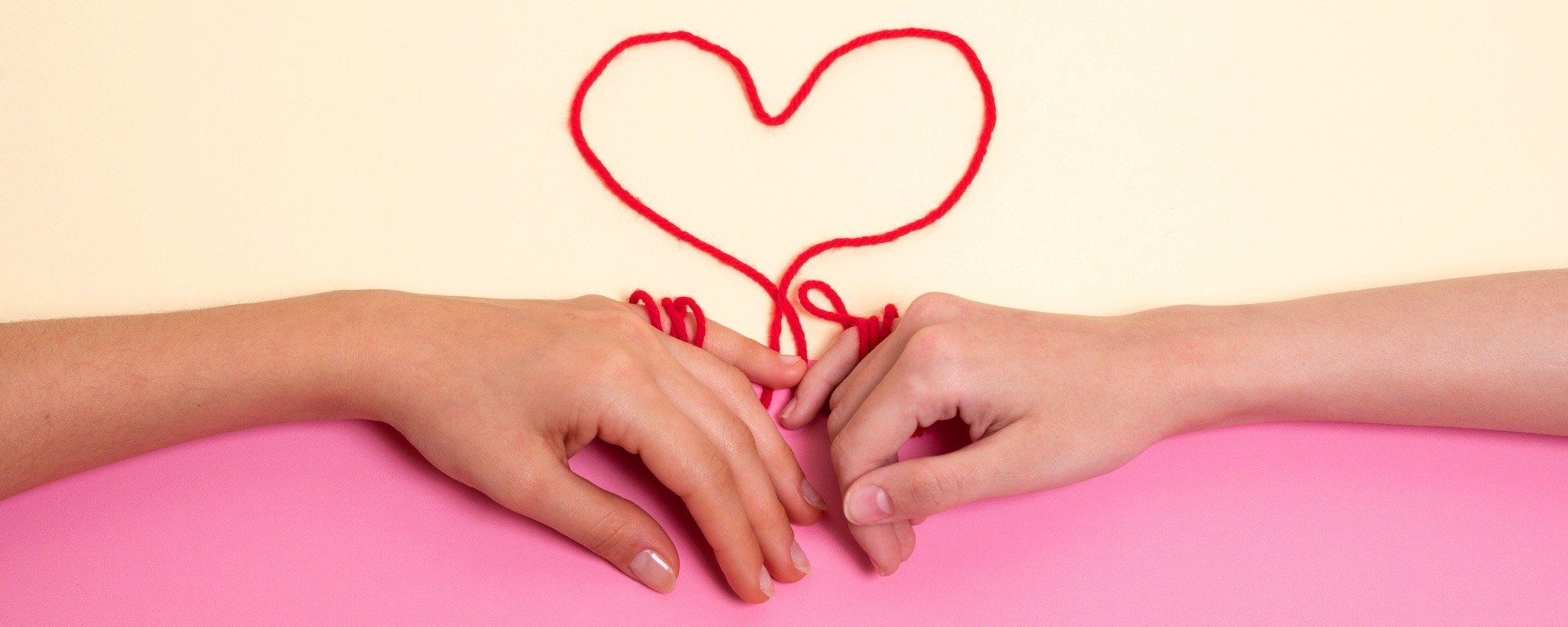Manos atadas con hilo rojo en forma de corazón luego de escuchar canciones de amor en inglés